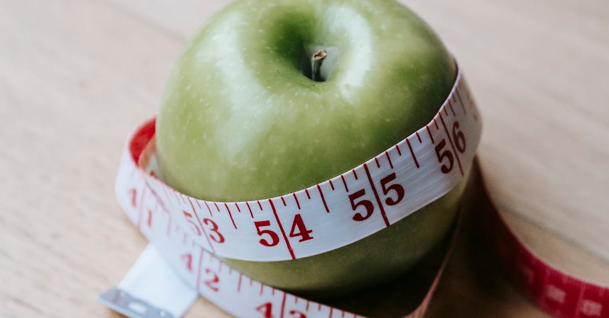 A green apple encircled by a measuring tape, symbolizing diet and fitness goals.
